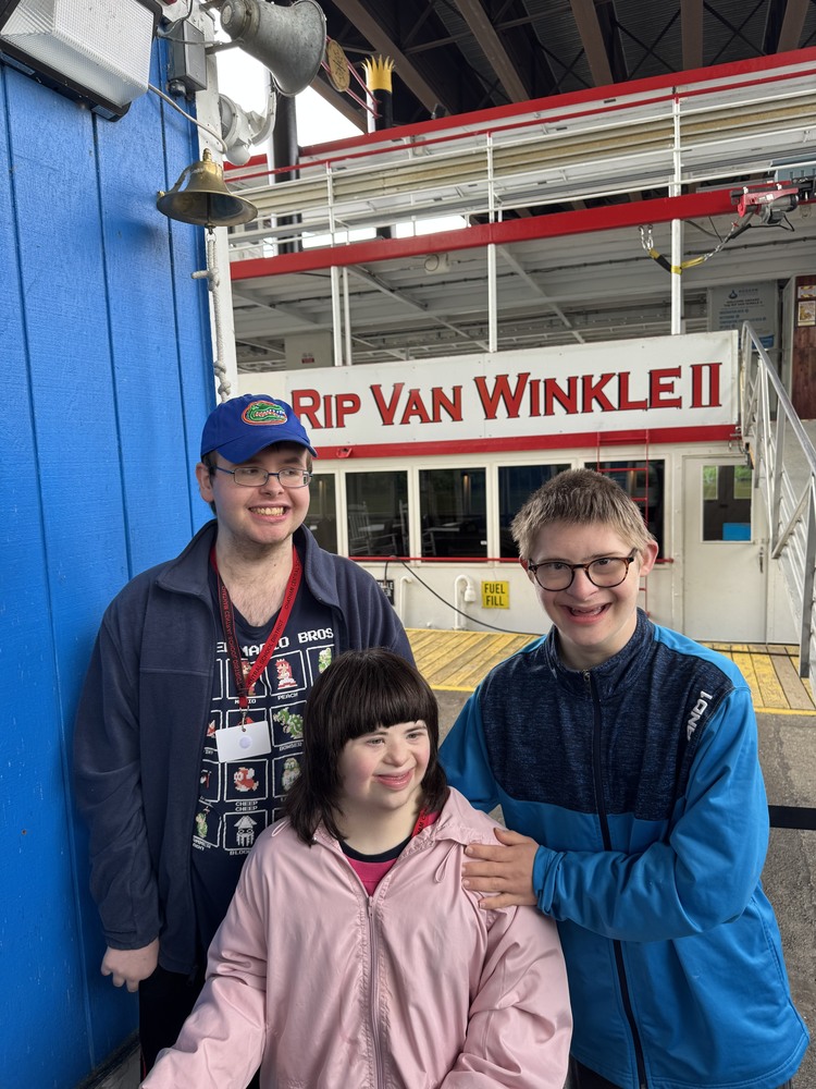 two boys and one girl standing alongside tourboat