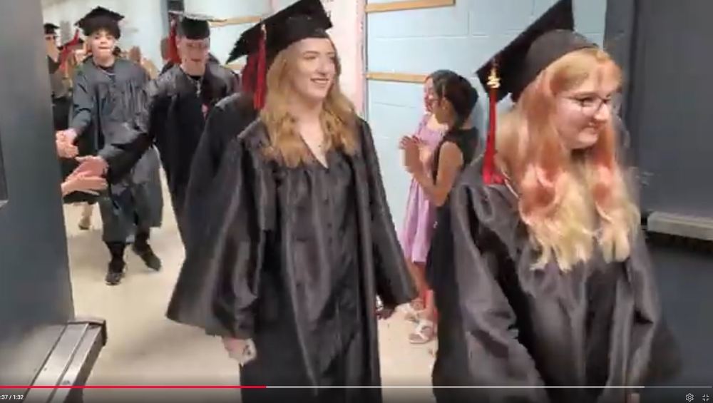 seniors in cap and gowns walking through hallway